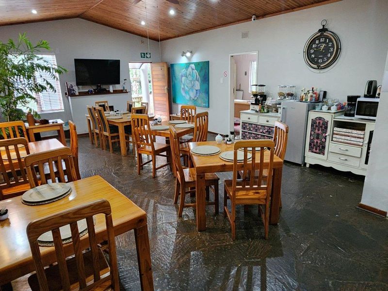 Spacious dining area featuring a vaulted timber ceiling, stone tile flooring, and a rustic brick feature wall, suitable for guest house dining.