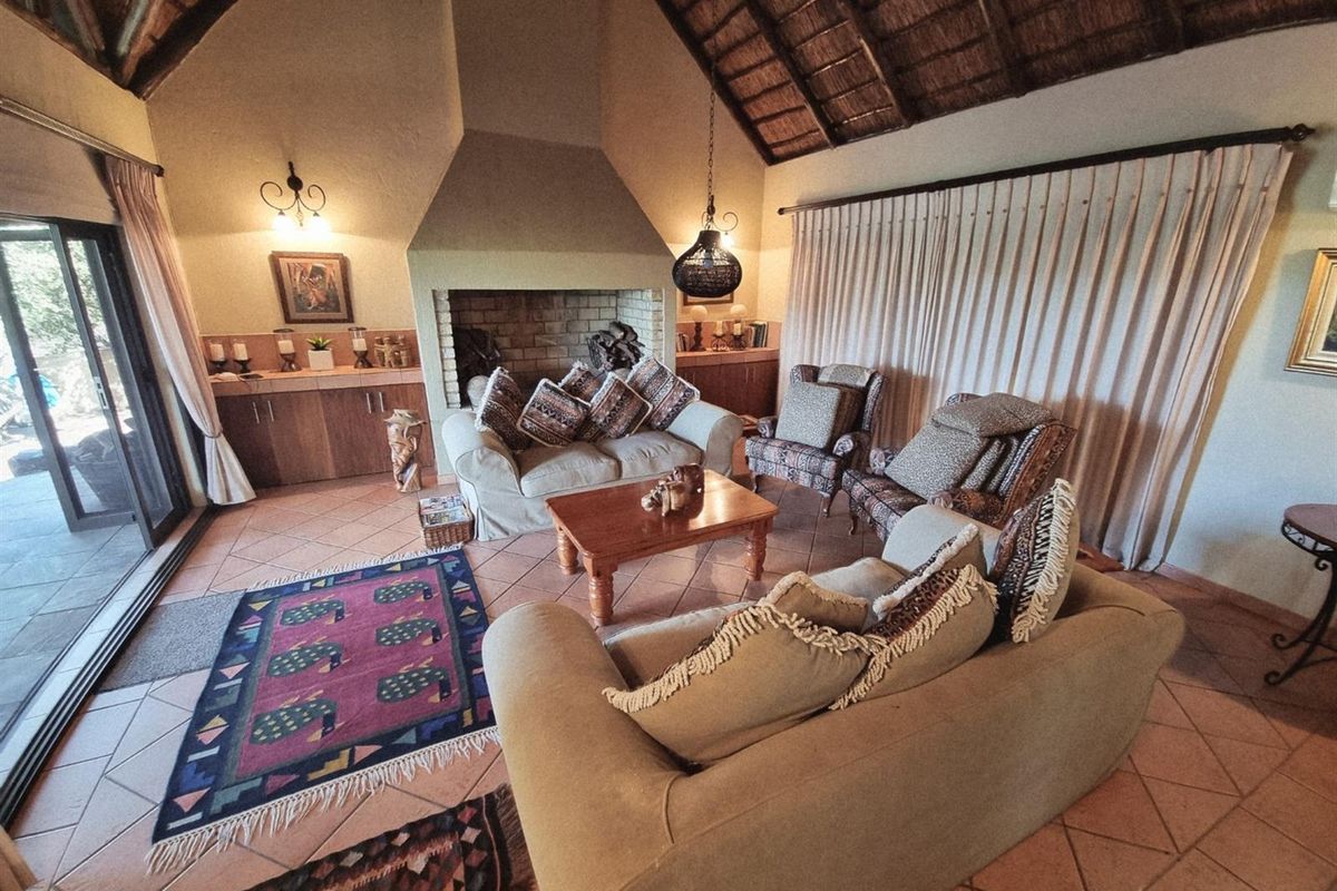 Spacious living room featuring a high vaulted thatched ceiling, large brick fireplace, and sliding glass doors leading to the outdoor area.