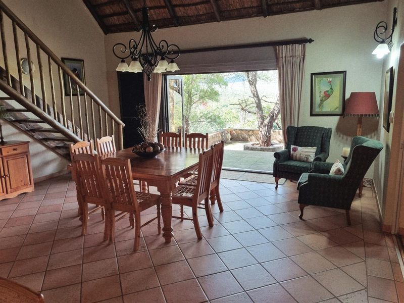 Spacious open-plan dining and living area featuring terracotta floor tiles, a vaulted thatched ceiling, and large sliding doors opening to a patio.