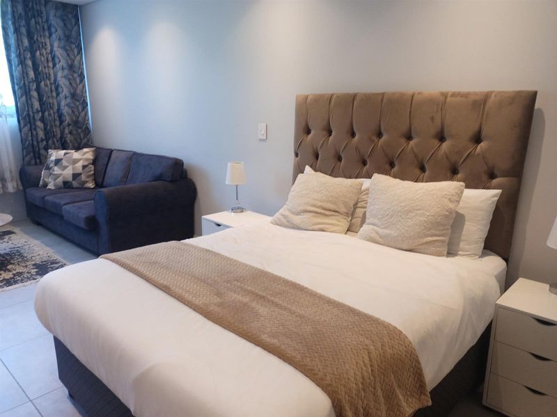 A well-maintained bedroom featuring neutral wall finishes, tiled flooring, and recessed downlighting, providing a comfortable and functional living space.