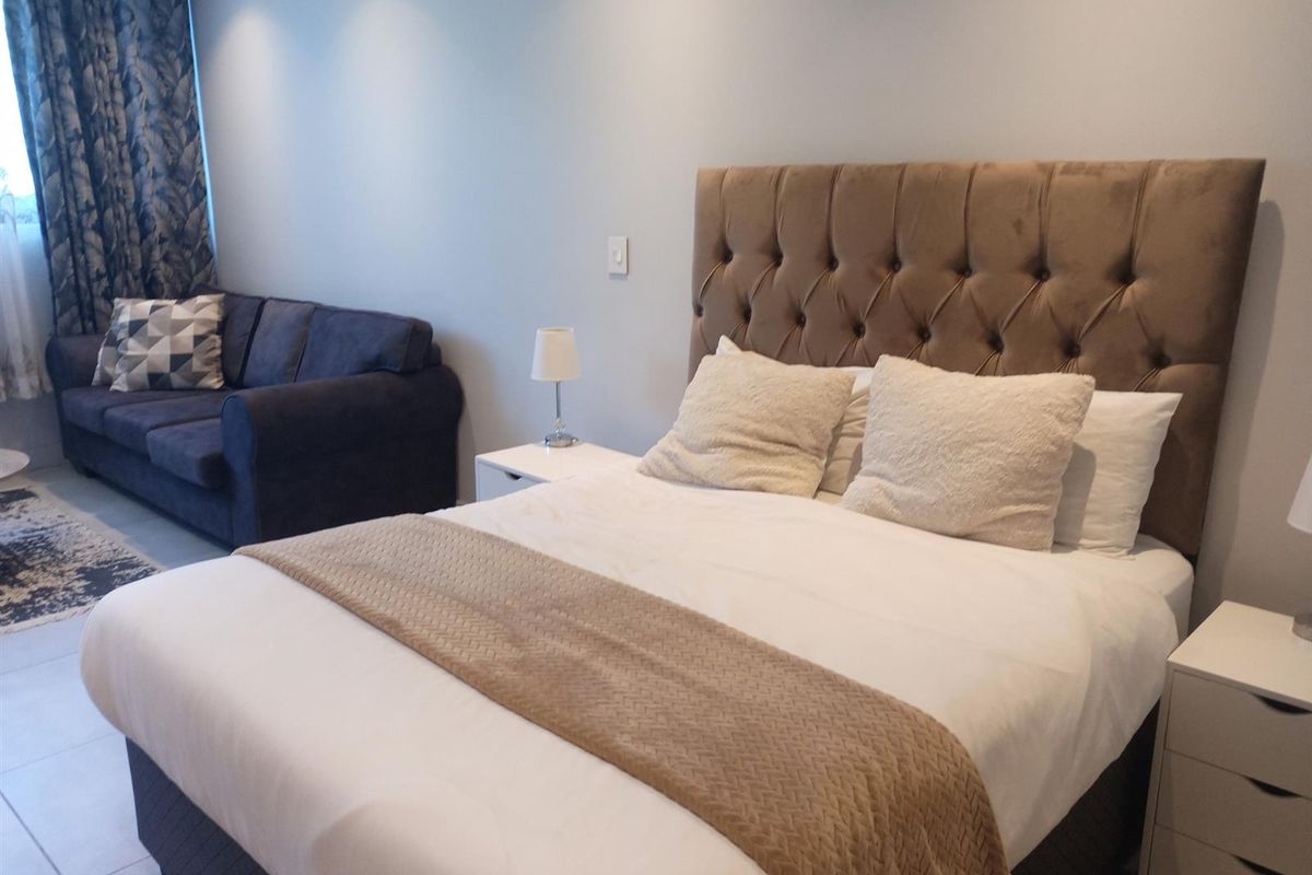 A well-maintained bedroom featuring neutral wall finishes, tiled flooring, and recessed downlighting, providing a comfortable and functional living space.