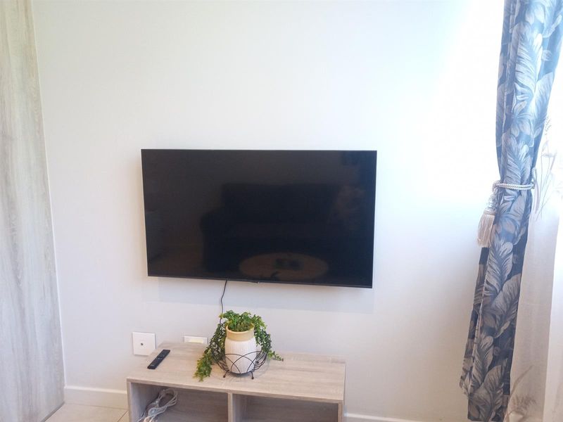 A view of a living area wall featuring a wall-mounted television and neutral interior finishes.