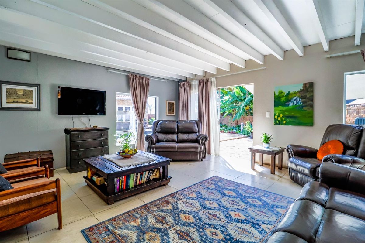Spacious living room featuring exposed white timber ceiling beams, neutral tiled flooring, and direct access to an outdoor patio area.