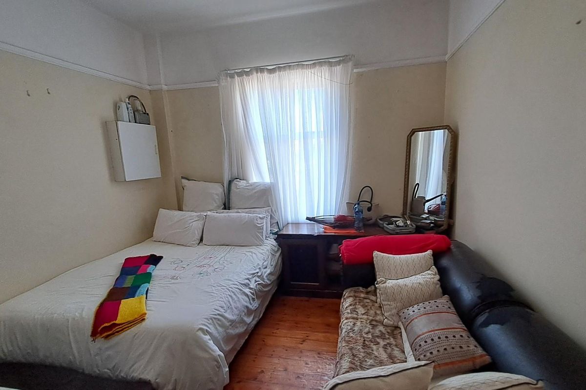 A compact bedroom featuring original hardwood flooring and a picture rail, requiring cosmetic updates to improve the overall aesthetic and finish.