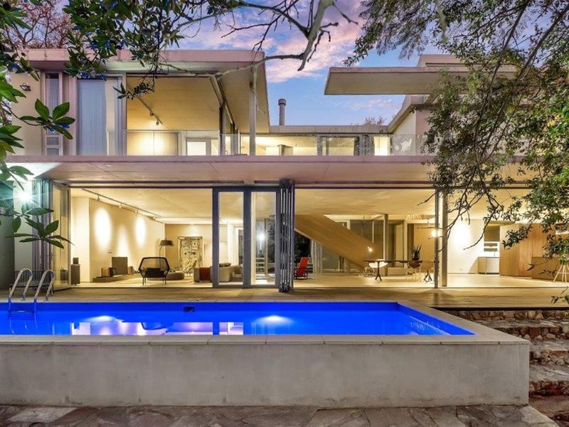 Modern architectural residence featuring expansive glass walls, a seamless indoor-outdoor flow, and a private swimming pool set within a landscaped garden.