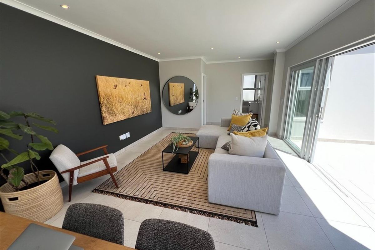 Modern living room featuring large sliding glass doors leading to an outdoor area, recessed ceiling lighting, and a striking dark feature wall.