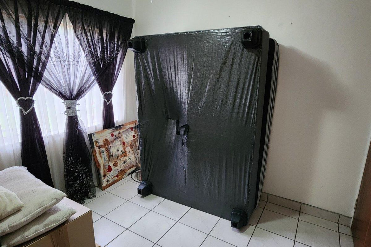 A bedroom featuring tiled flooring and a built-in cupboard, currently used for storage.