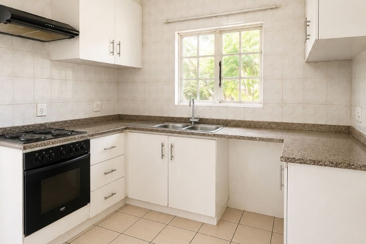 A clean, functional kitchen featuring white cabinetry, laminate countertops, a built-in oven with gas hob, and neutral ceramic floor tiles.
