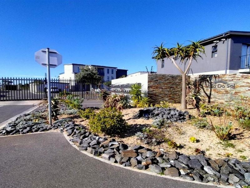 The front entrance of the apartment complex features secure gated access, stone-clad feature walls, and a well-maintained landscaped garden area.