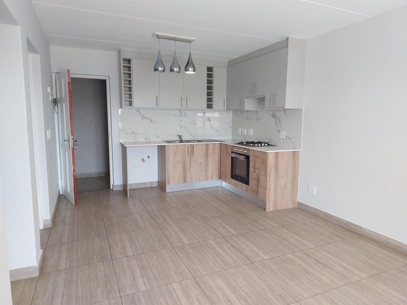 Modern kitchen featuring light wood-tone cabinetry, marble-look splashback, integrated oven, gas hob, and neutral tiled flooring in an open-plan layout.