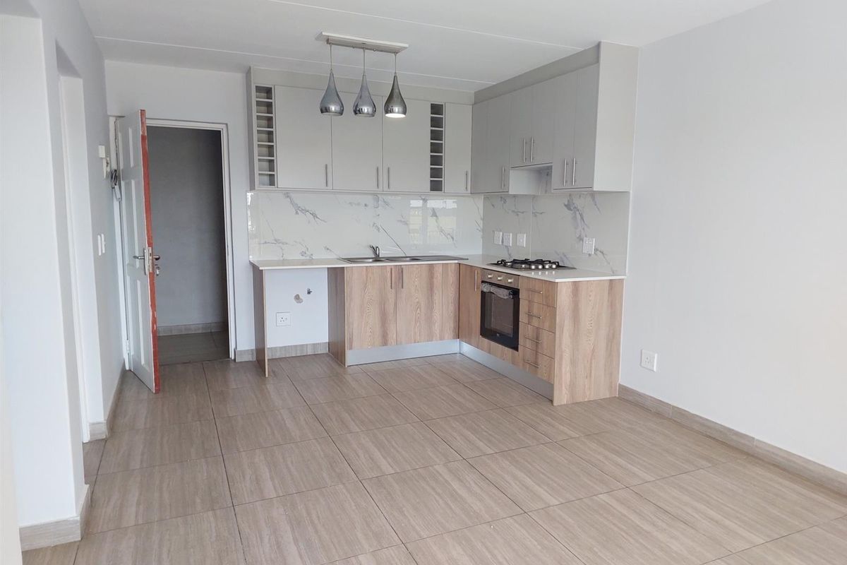 Modern kitchen featuring light wood-tone cabinetry, marble-look splashback, integrated oven, gas hob, and neutral tiled flooring in an open-plan layout.