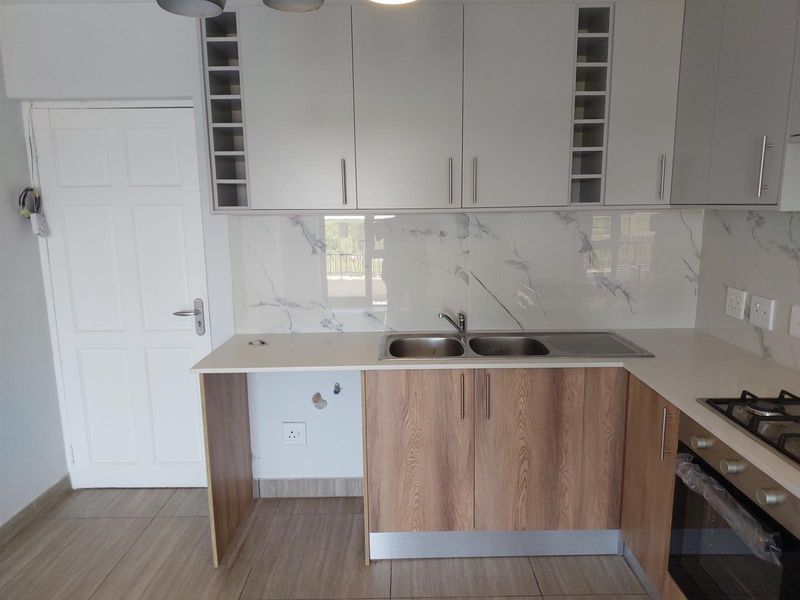 Modern kitchen featuring two-tone cabinetry, marble-look splashback, integrated oven, gas hob, and double bowl sink with an open space for an appliance.