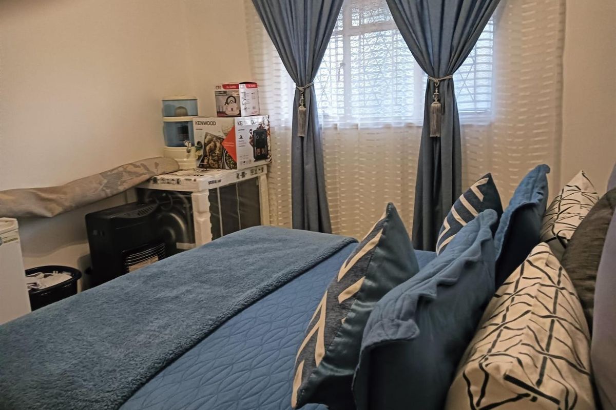 A bedroom featuring a window with blue curtains and neutral wall finishes.