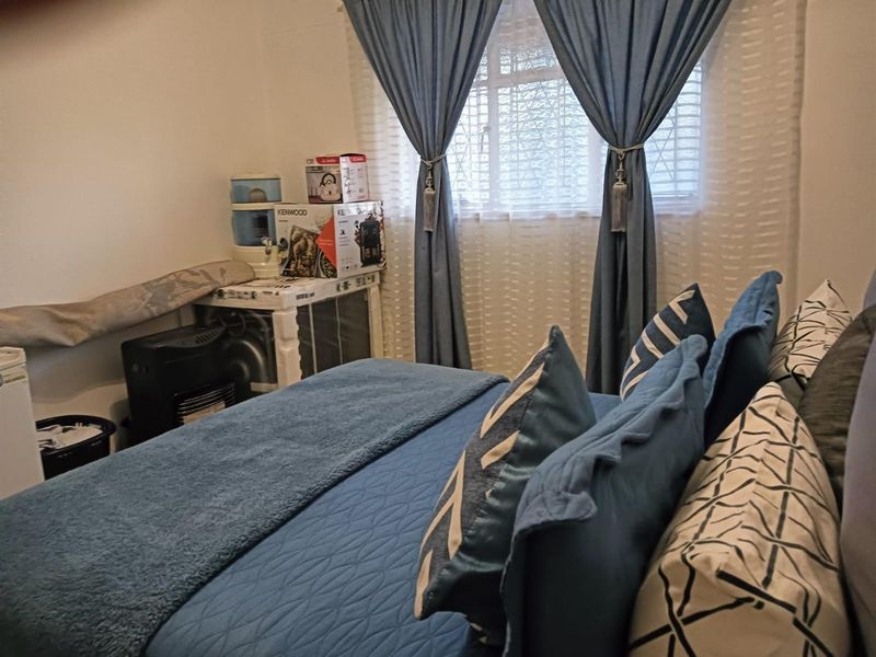 A bedroom featuring a window with blue curtains and neutral wall finishes.