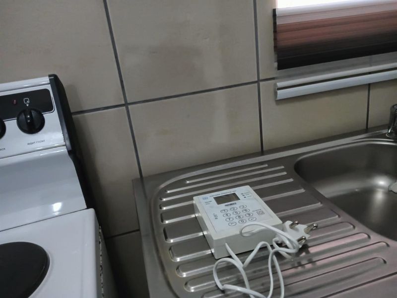 A close-up view of a kitchen area featuring a stainless steel sink, tiled backsplash, and a white stove.