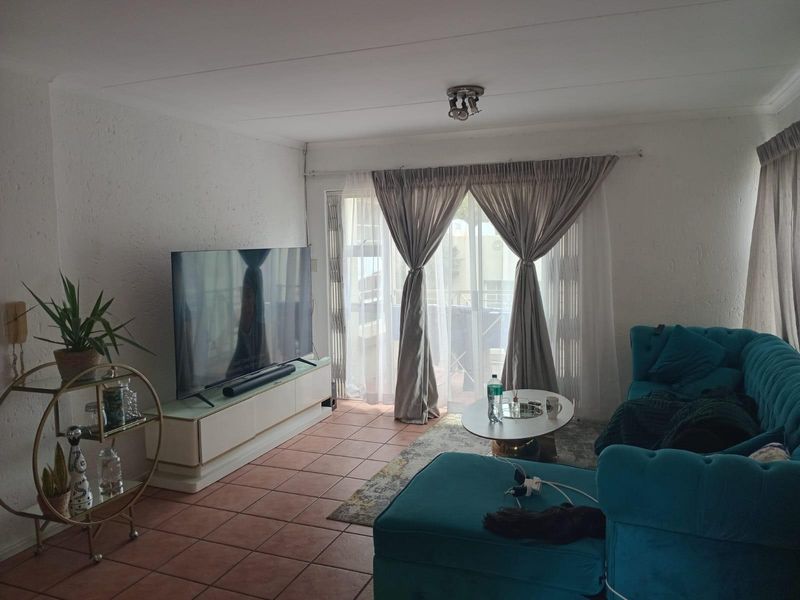 A living room featuring terracotta floor tiles and a sliding glass door providing access to an outdoor area.