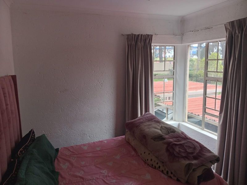 A bedroom featuring a bay window with curtain tracks and textured wall finishes, offering natural light and a view of the surrounding area.