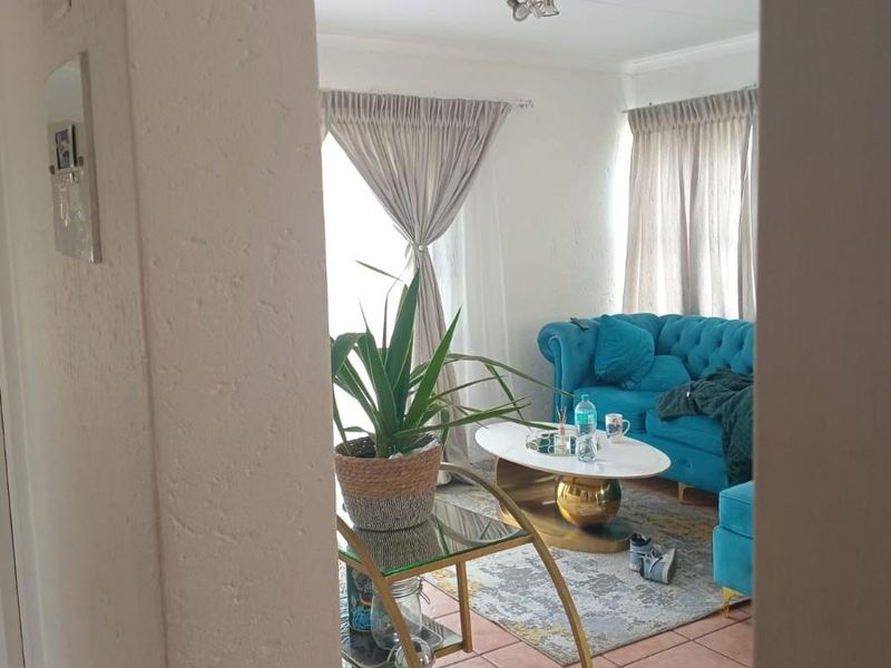 A view into a living room featuring tiled flooring and a ceiling-mounted spotlight fixture, viewed through a doorway.