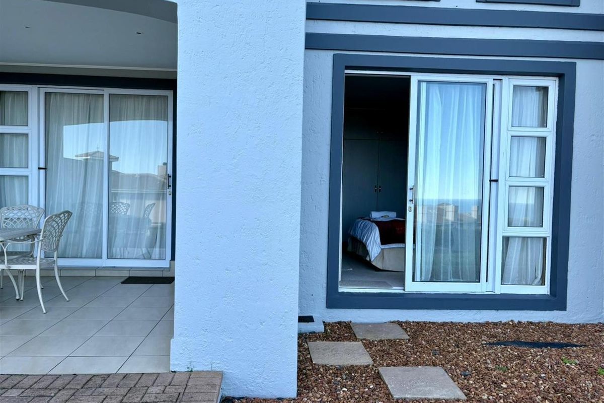 Exterior view of a townhouse featuring a covered patio area and sliding glass doors providing access to an interior bedroom.