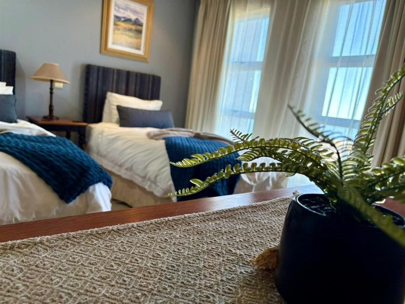 A bedroom featuring large windows with natural light, neutral wall tones, and space for twin beds.