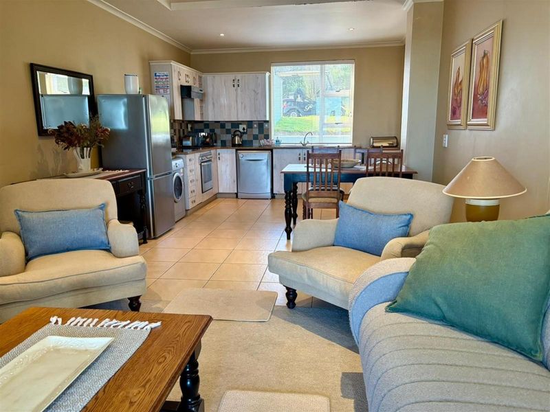 Open-plan living and kitchen area featuring tiled flooring, built-in cabinetry, and integrated kitchen appliances, creating a functional and connected living space.