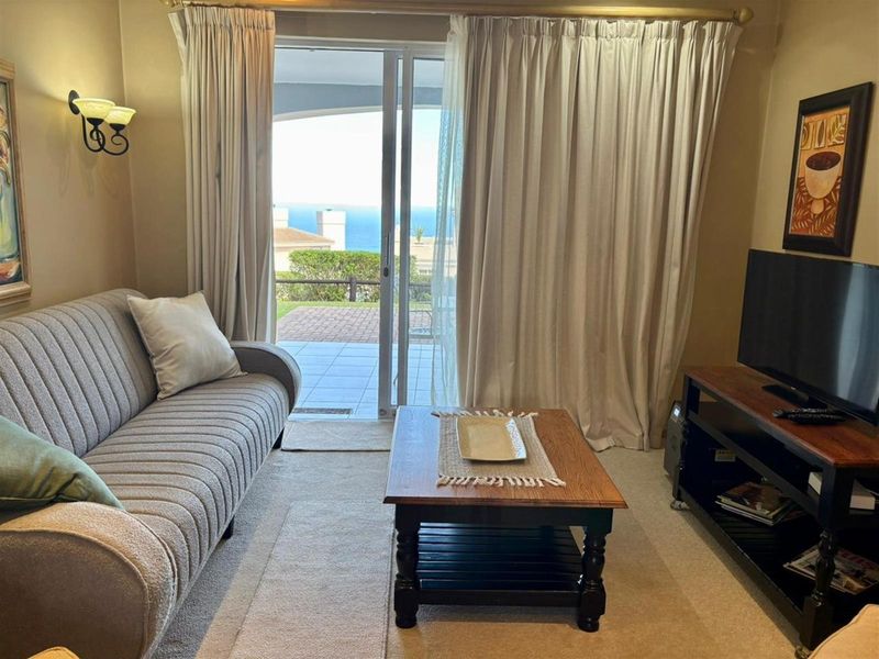 A cozy living room featuring sliding glass doors that open to a patio with scenic ocean views.