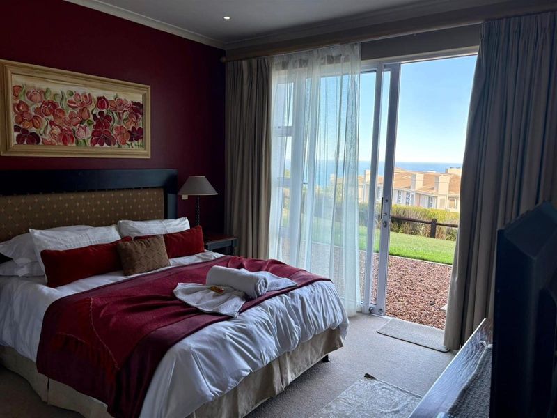A bedroom featuring sliding glass doors that open to a patio with scenic coastal views.
