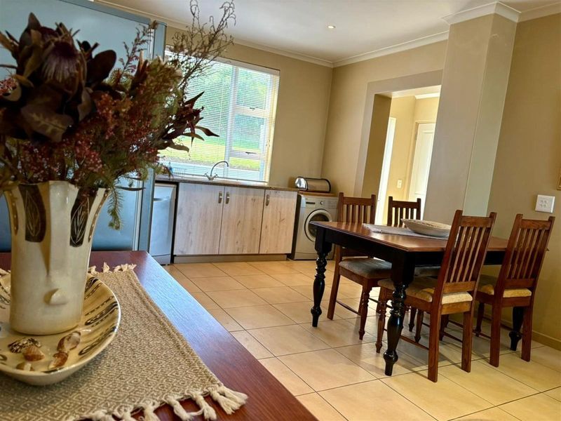 Open plan kitchen and dining area featuring tiled flooring, built-in cabinetry, and a dedicated laundry space with appliance connections.