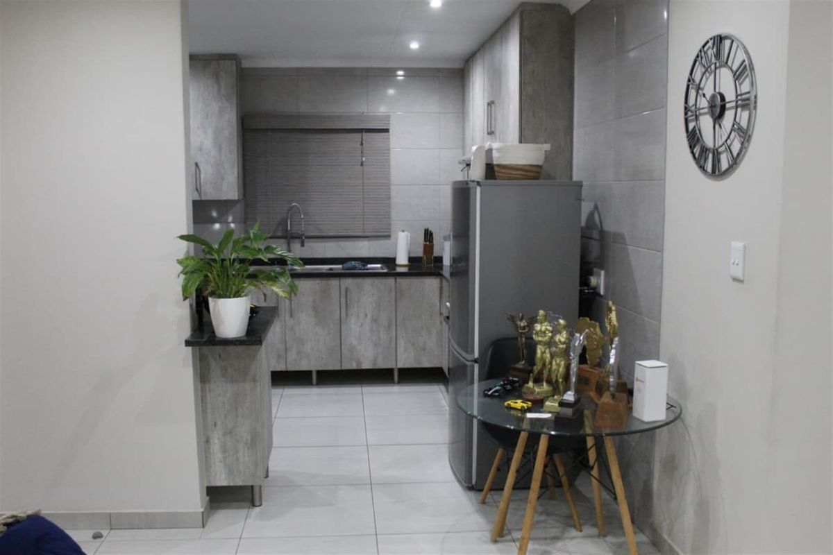 Modern kitchen featuring grey wood-look cabinetry, granite countertops, tiled splashbacks, and integrated lighting, offering a clean and functional workspace.