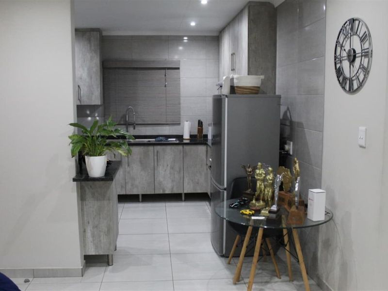 Modern kitchen featuring grey wood-look cabinetry, granite countertops, tiled splashbacks, and integrated lighting, offering a clean and functional workspace.