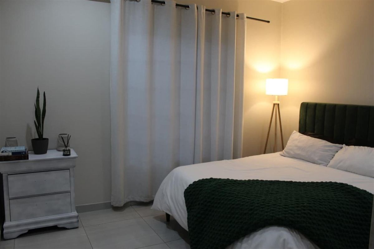 A well-maintained bedroom featuring neutral wall tones, tiled flooring, and a curtain rod, providing a comfortable and functional sleeping space.