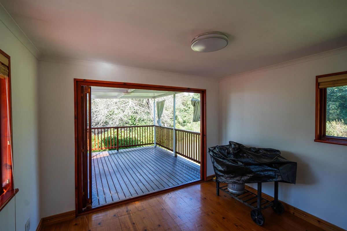 Interior living space featuring polished timber flooring and large bi-fold doors opening onto an elevated timber deck with outdoor railing.