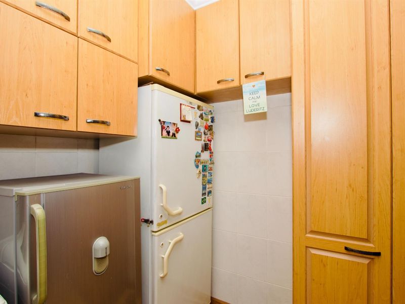 A functional kitchen area featuring light wood cabinetry, tiled splashbacks, and dedicated space for refrigeration units.