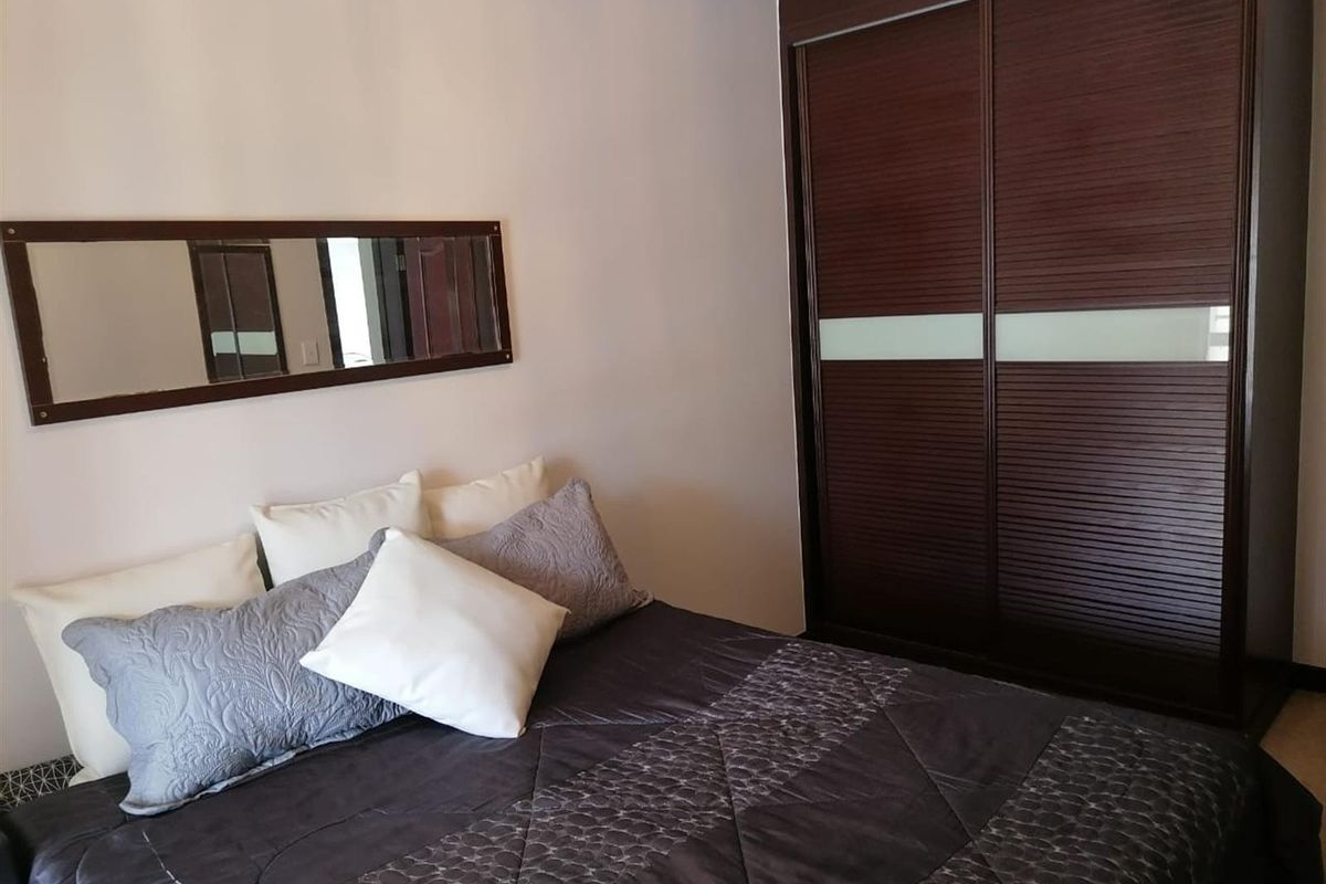 A bedroom featuring a built-in dark wood sliding door wardrobe with integrated glass panels.