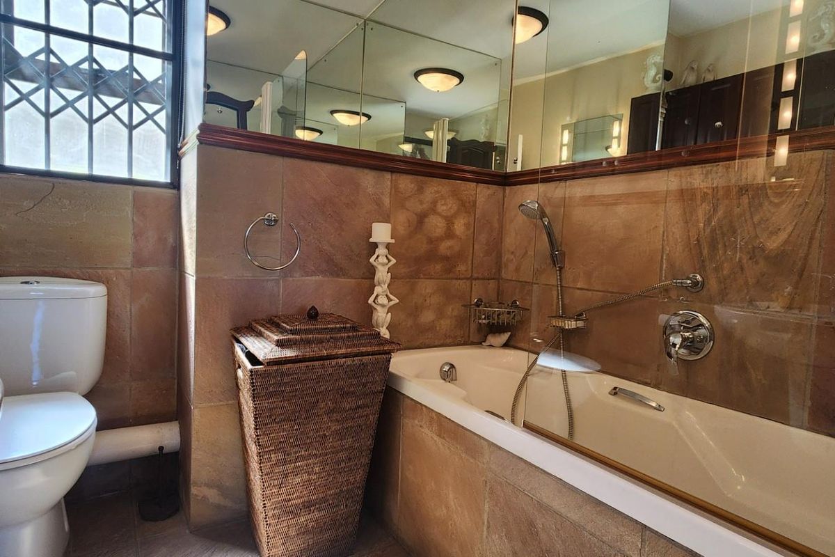 A functional bathroom featuring a built-in bathtub with shower attachment, wall-mounted mirror, and tiled walls.