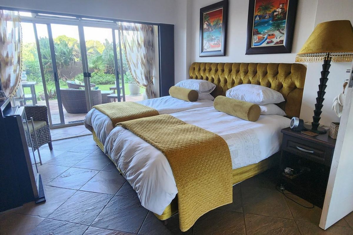 A bedroom featuring tiled flooring and large sliding glass doors that provide direct access to an outdoor patio area.