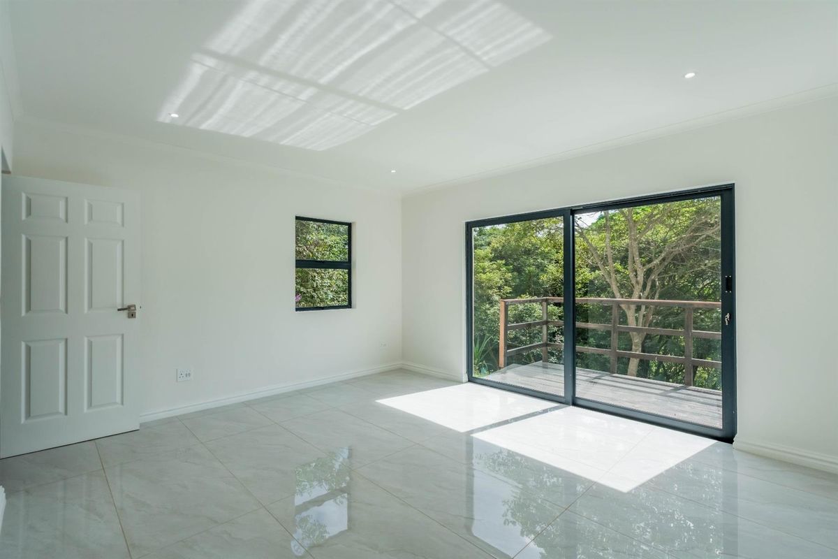 Bright and spacious bedroom featuring polished porcelain floor tiles, recessed downlighting, and large sliding glass doors opening onto a private wooden balcony.