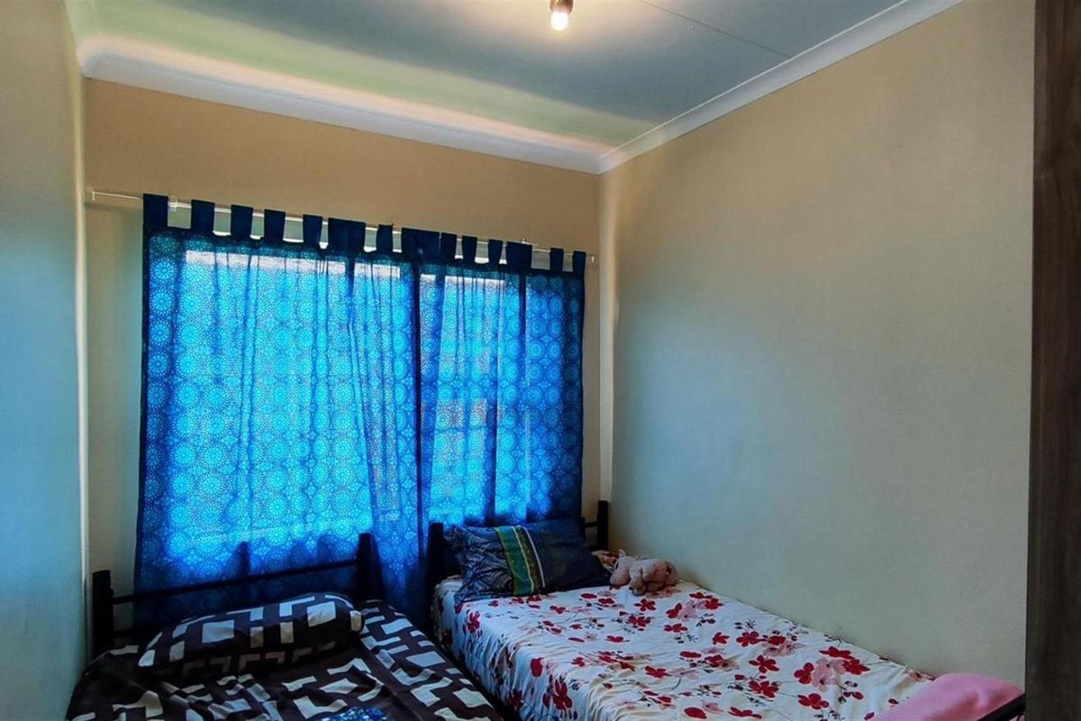 A standard bedroom featuring neutral wall finishes, coved ceiling cornices, and a window fitted with a curtain rod.