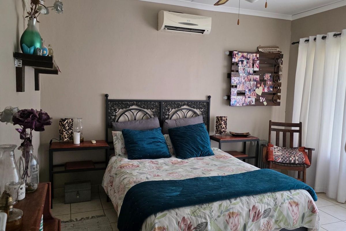 A bedroom featuring tiled flooring and a wall-mounted split-system air conditioning unit, providing a functional and comfortable living space.