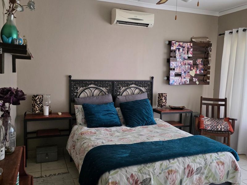A bedroom featuring tiled flooring and a wall-mounted split-system air conditioning unit, providing a functional and comfortable living space.
