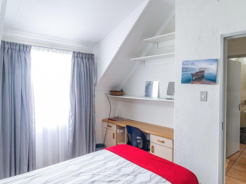 Bedroom featuring a built-in desk, sloped ceiling, and direct access to an en-suite bathroom with tiled flooring.