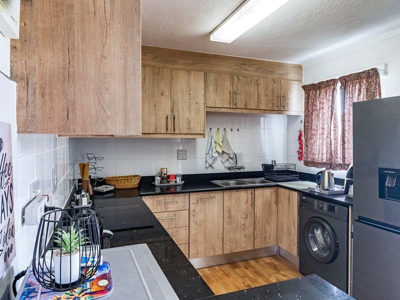 A functional kitchen featuring wood-look laminate cabinetry, black granite countertops, a double bowl sink, and an integrated washing machine.