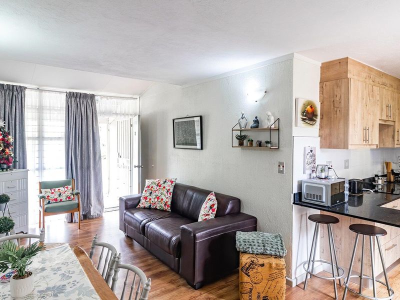 Open-plan living area featuring a modern kitchen with granite countertops, integrated appliances, and direct access to an outdoor patio through sliding glass doors.