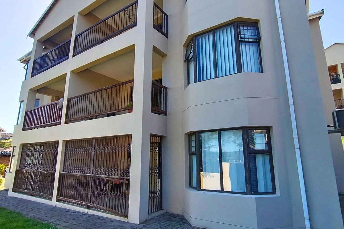 Exterior view of an apartment building featuring multiple levels of balconies with metal railings, security gates, and large bay windows.