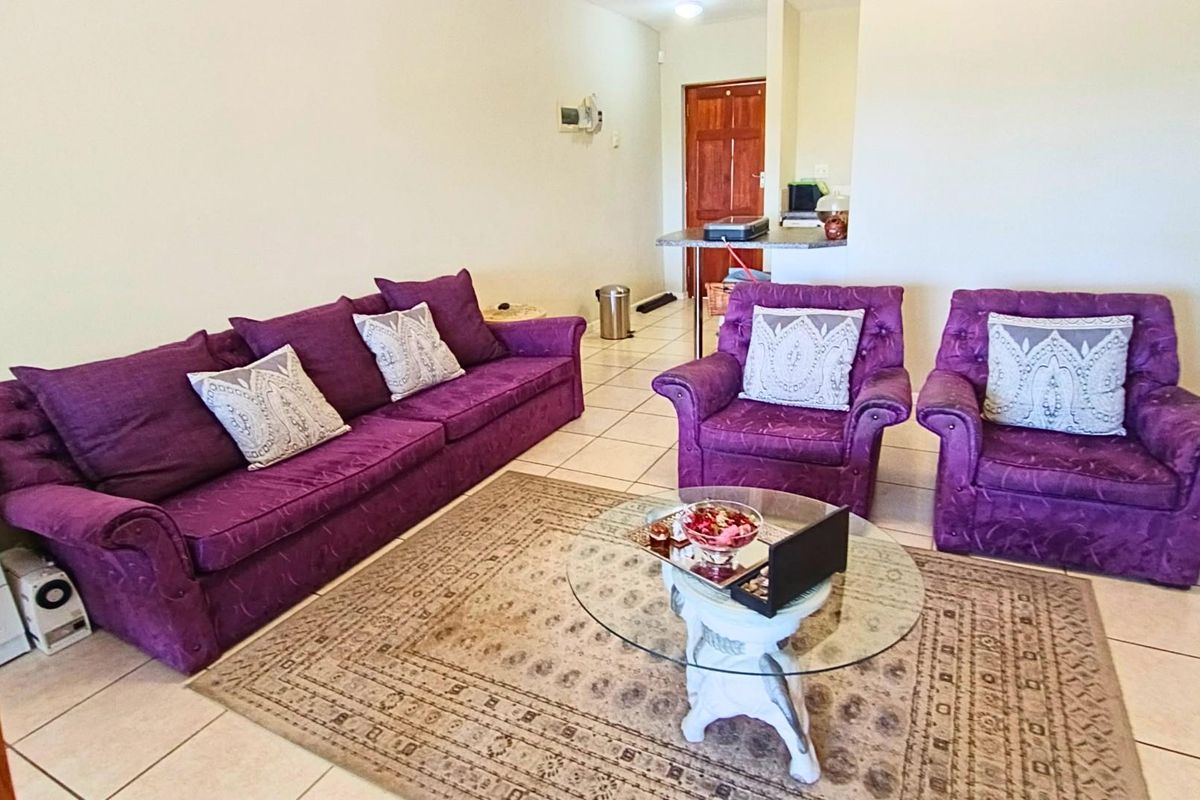 A living room area featuring ceramic floor tiles and a breakfast bar leading to an adjacent space with a wooden door.