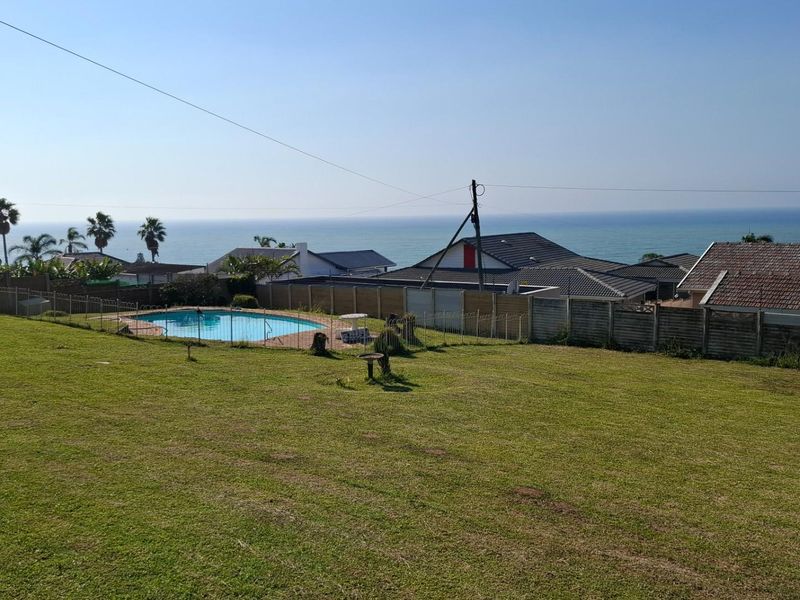 Expansive backyard area featuring a swimming pool with a scenic ocean view and established perimeter fencing.