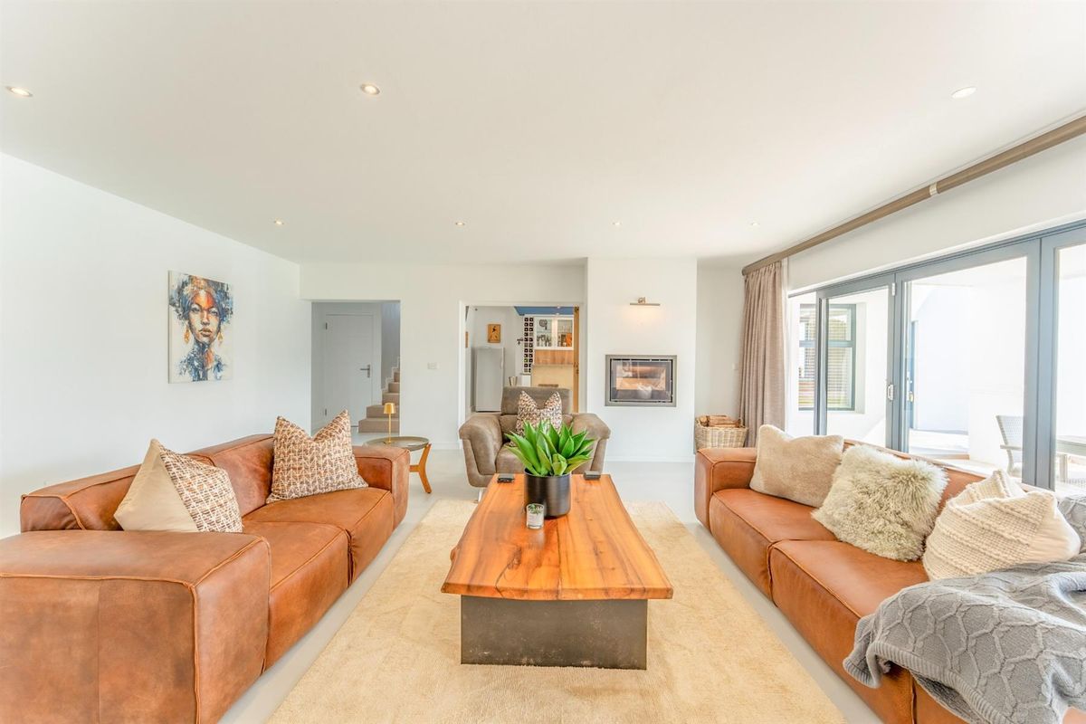 Spacious open-plan living area featuring a built-in fireplace, recessed ceiling lighting, and large sliding glass doors providing access to the outdoor patio.