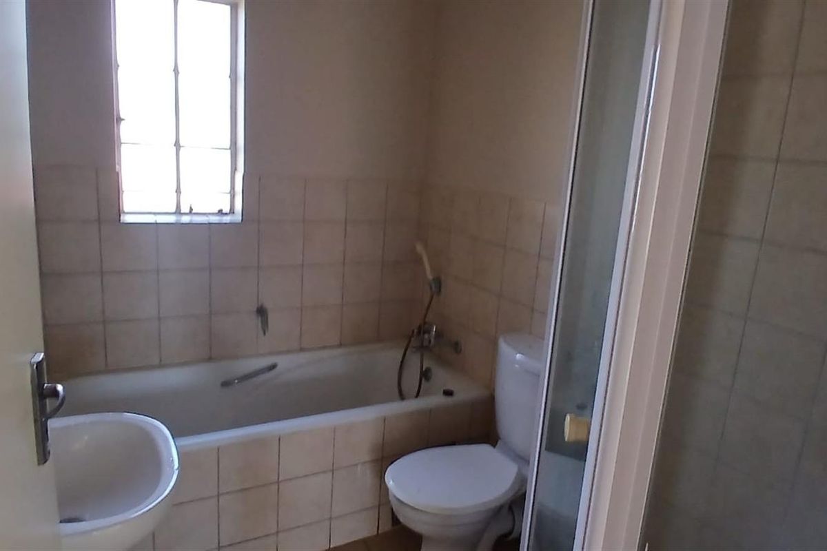 A functional bathroom featuring a bathtub with shower attachment, a toilet, and a separate shower enclosure with tiled walls.