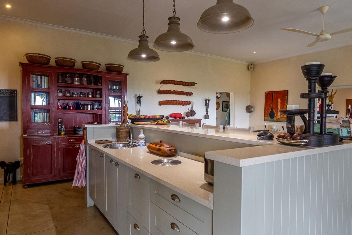 A spacious kitchen featuring a large central island with stone countertops, integrated sink, and classic cabinetry, complemented by overhead pendant lighting.