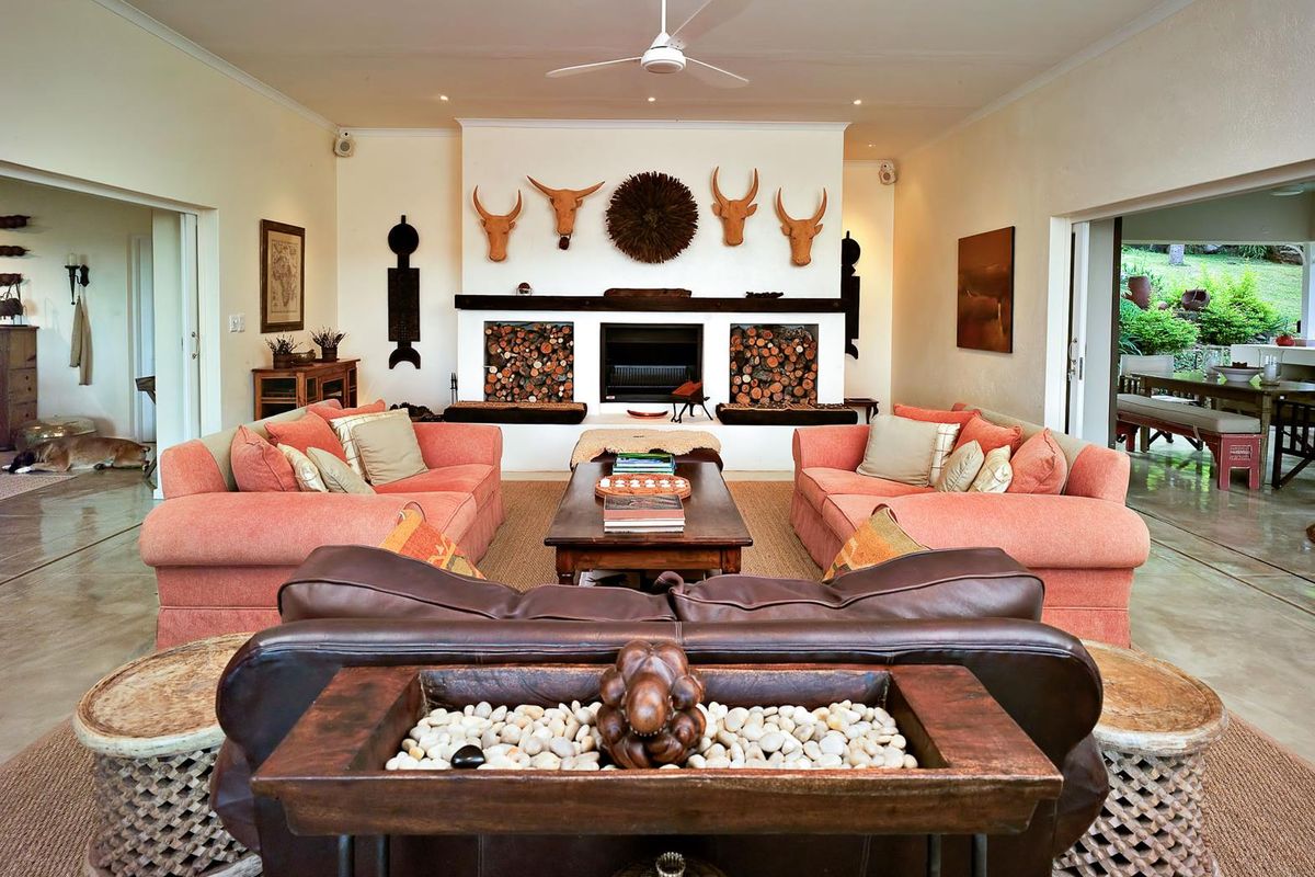 Spacious living room featuring a large central fireplace with built-in log storage and recessed ceiling lighting, opening onto an adjacent dining area.